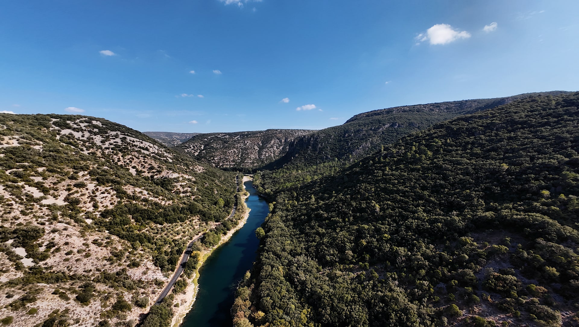 Vue en hauteur de la rivière et de la route entre les versants rocheux et boisés des gorges de l'Hérault.