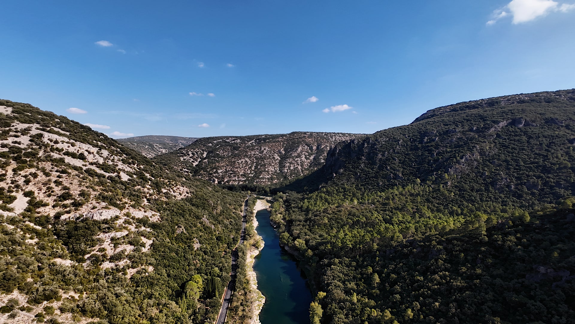 L'Hérault entre deux versants rocheux et boisés, avec une route longeant la rivière, vu en hauteur depuis un DJI Avata 2.