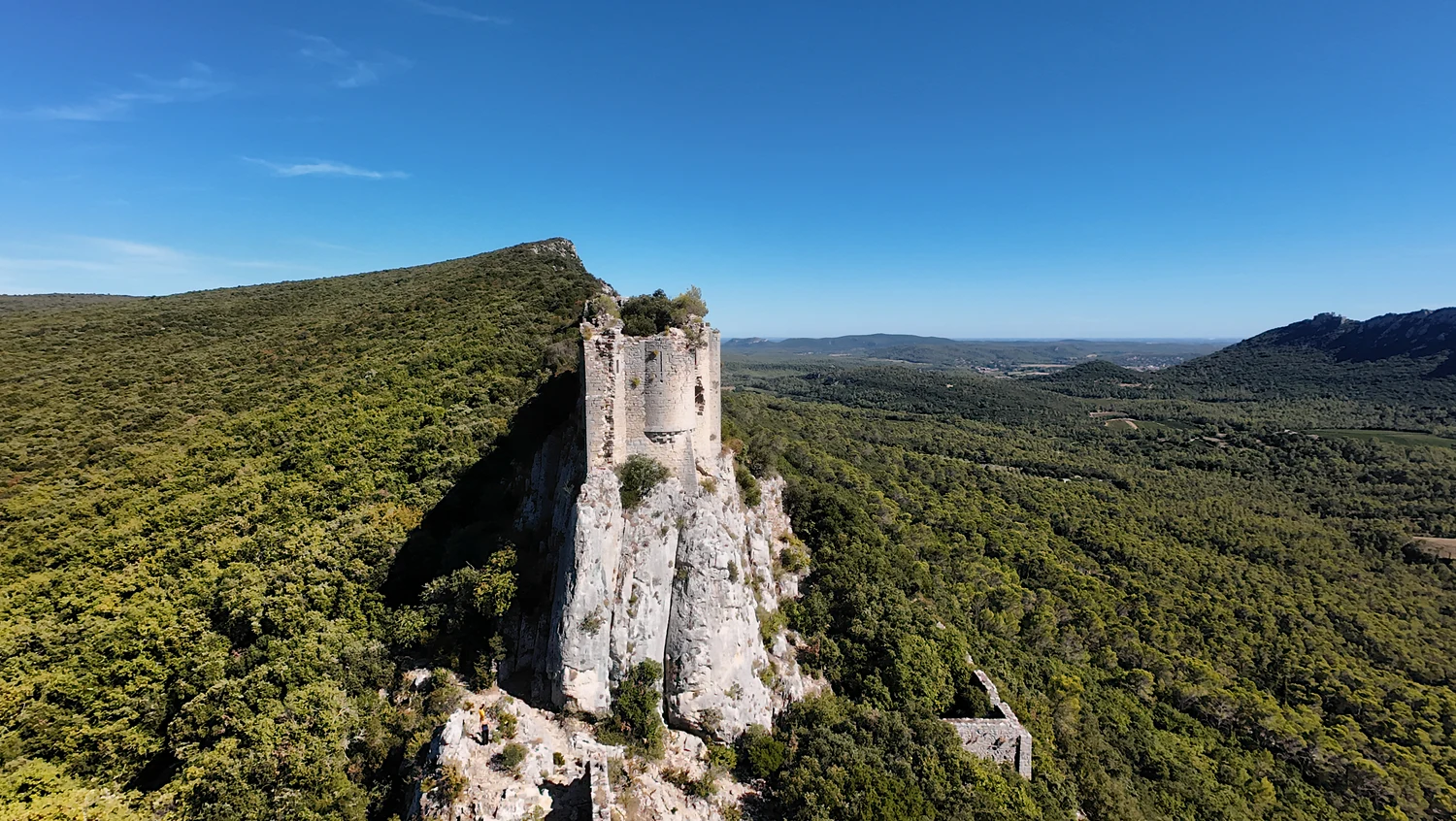 Haute maçonnerie de Viviourès sur un éperon calcaire clair, au-dessus des arbres, avec des pans de murs plus bas.