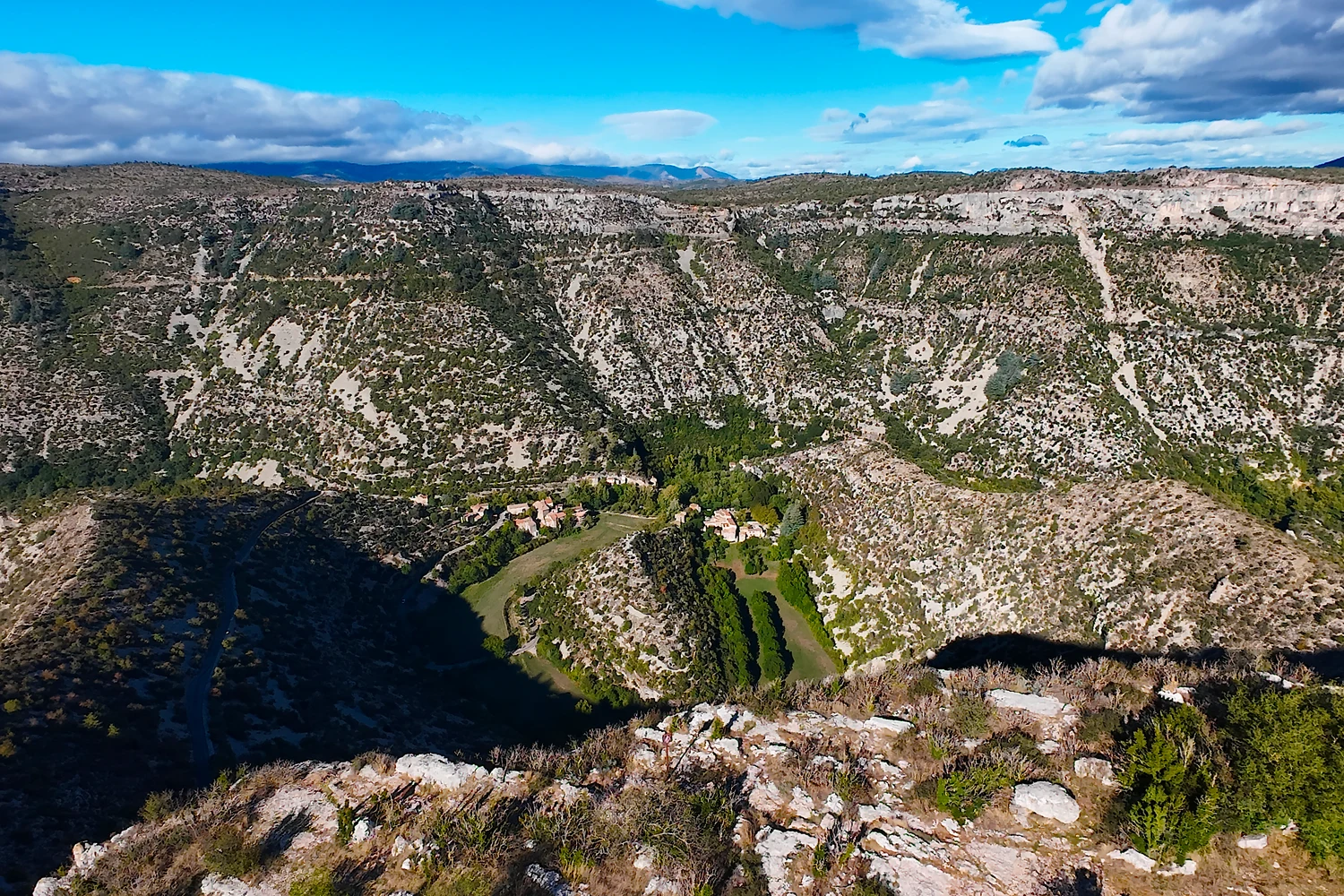 Le cirque et son ancien méandre vus au DJI Avata 2, avec des roches au bas du cadre et les falaises à l’arrière-plan.